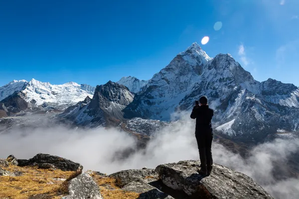 A trekker capturing Ama Dablam as clouds roll through the Imja Valley