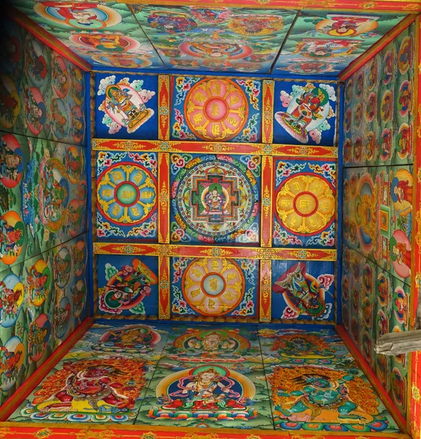 Bright hand-painted mandalas and sacred symbols decorating the ceiling of a mountain shrine