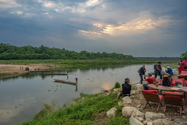 Visitors gathered at riverside tables watching the sun dip over the Rapti River