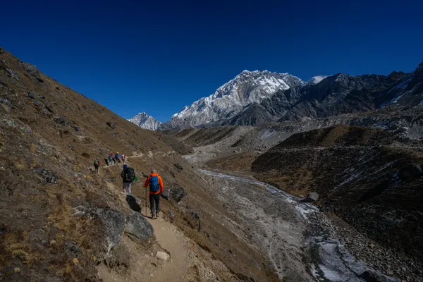 Hikers following the river valley toward the Cholatse massif