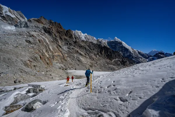 Trekkers navigating the snow-covered glacier near the Cho La Pass summit
