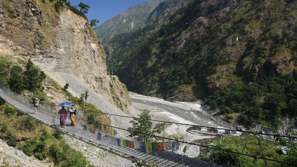 A suspension bridge swaying high above fast-moving river water