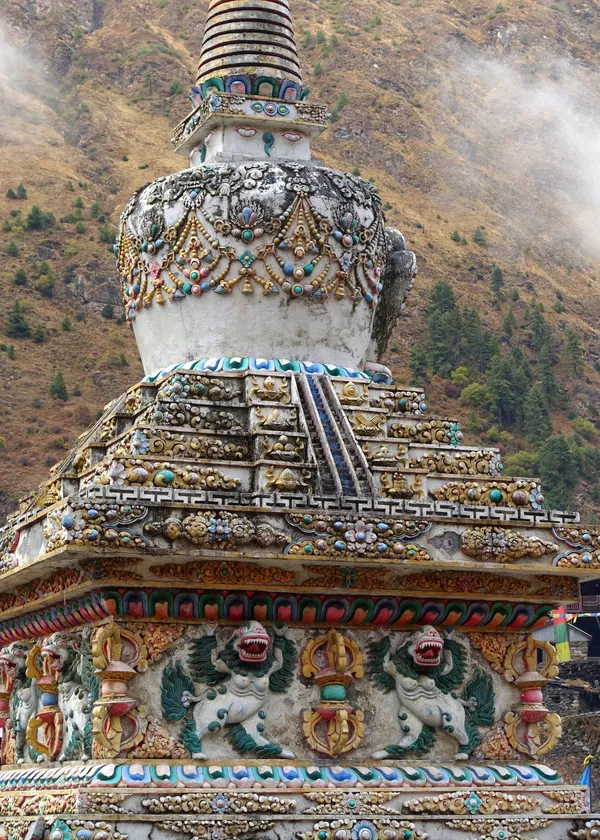 An intricately carved stone stupa adorned with colorful Buddhist symbols