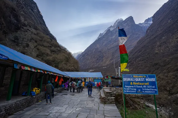 Blue-roofed Deurali Guest House beneath steep mountain walls