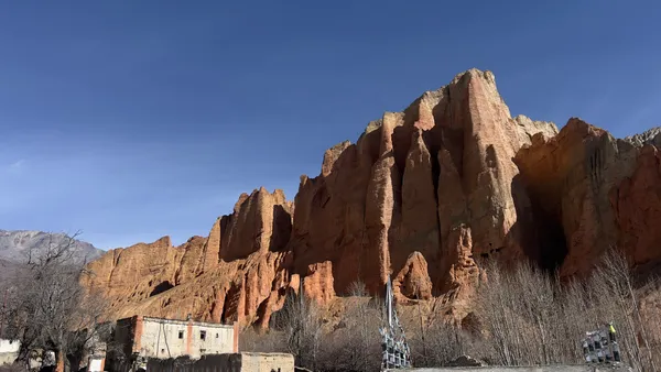 Ancient stone structures rising beneath the red cliffs of Dhakmar village