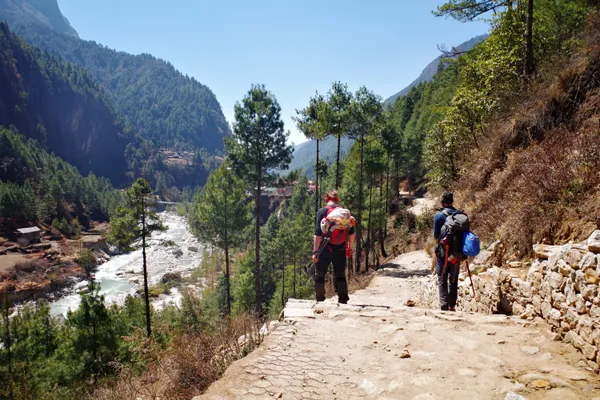 Trekkers descending toward Phakding along the glacial river valley