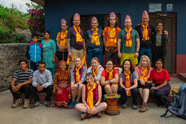 Trekkers and host family celebrating a farewell ceremony with traditional garlands