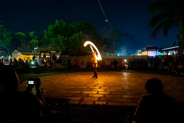 A performer spinning a blazing arc of fire during a nighttime cultural show