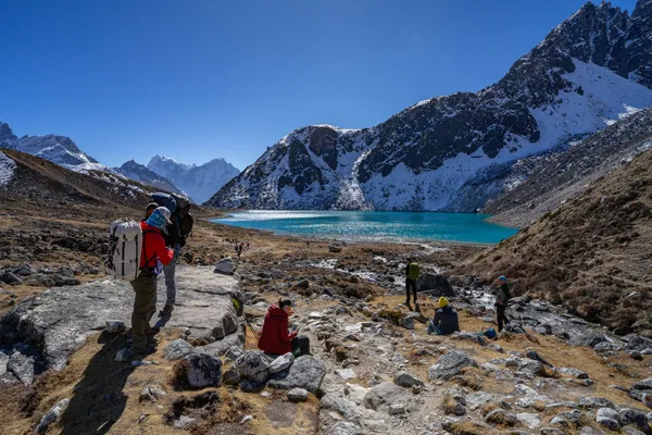 Trekkers pause by the turquoise waters of the first Gokyo Lake at 4,710 meters