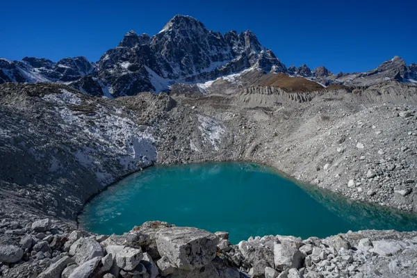 Turquoise waters of Longpongo Lake beneath the dramatic Cholatse peak