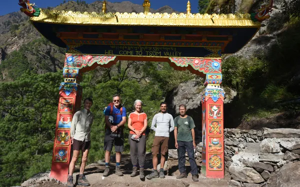 Trekkers beneath a colorful entrance gate with a golden roof