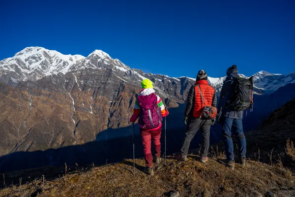 Trekkers pausing to absorb the massive face of Annapurna South and Hiunchuli