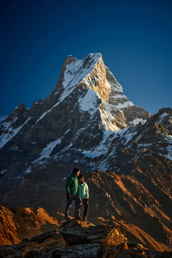Trekkers standing on the ridge as golden light gilds Machhapuchhre