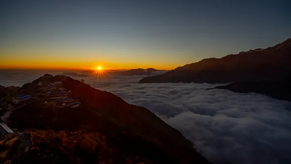 The sun cresting over a sea of clouds, bathing High Camp in morning light