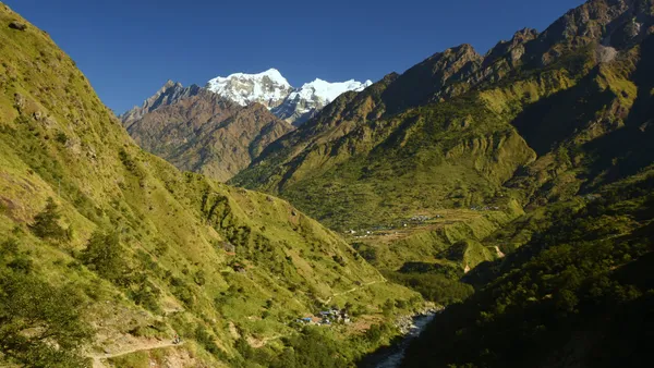 Lush green valleys sweeping toward white mountains