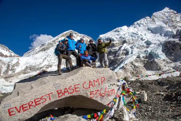 Trekkers celebrating at the Everest Base Camp marker at 5,364 m