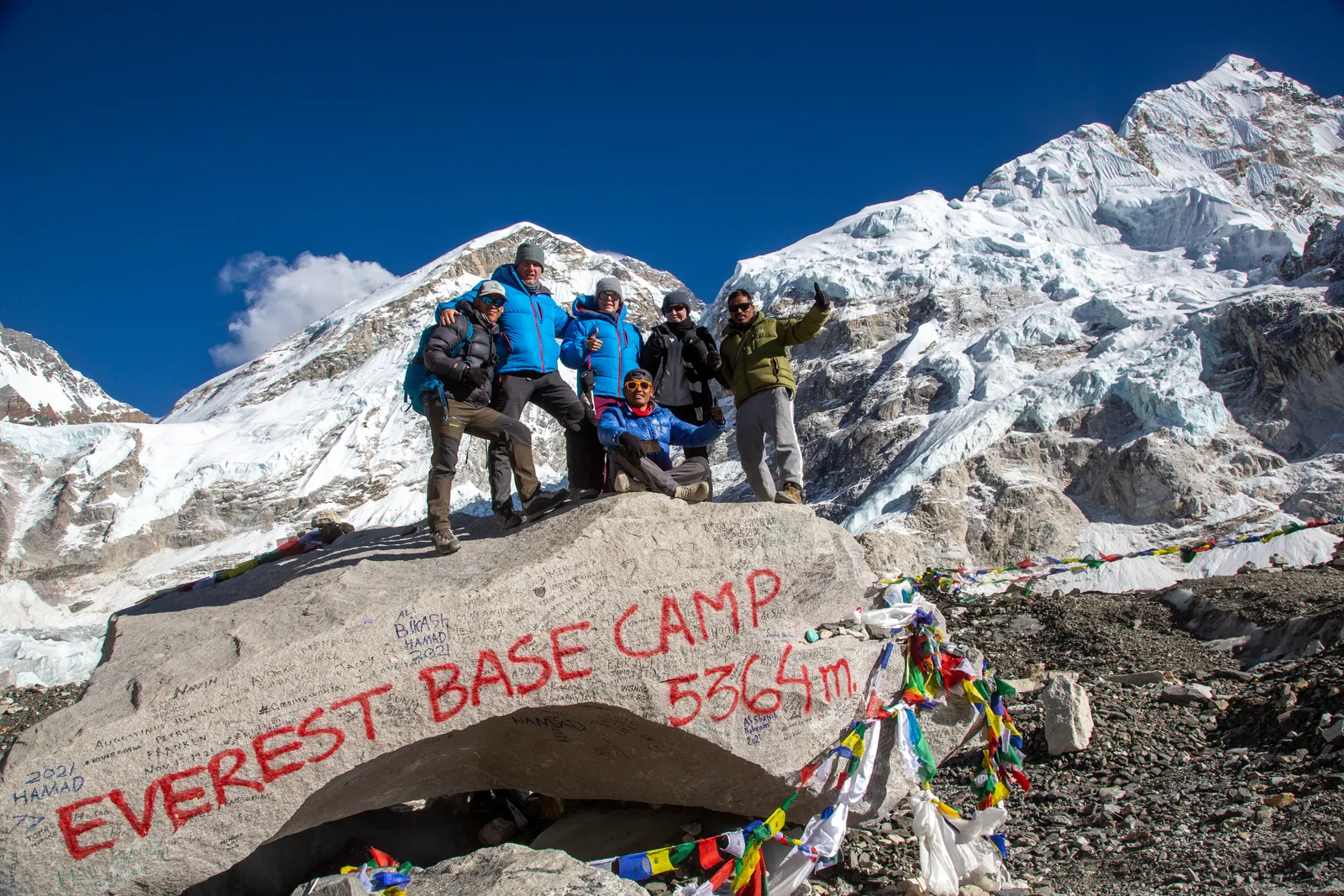 Trekkers celebrate at the official Everest Base Camp marker at 5,364 m