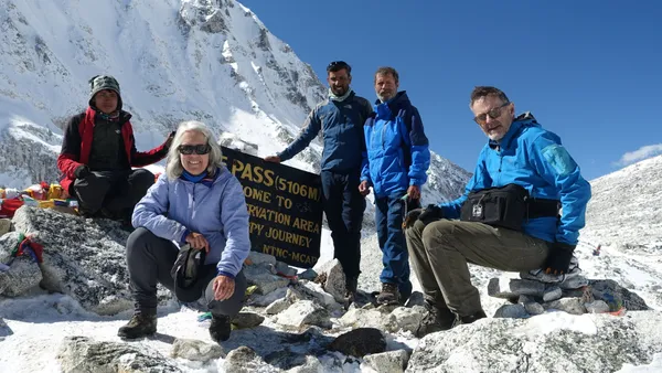 Elated trekkers celebrating at the Larkya La Pass sign at 5,160 meters