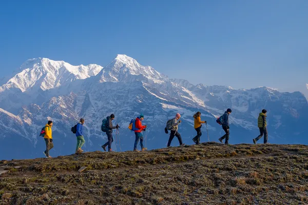 The team traversing the ridge in single file with the Annapurna range behind