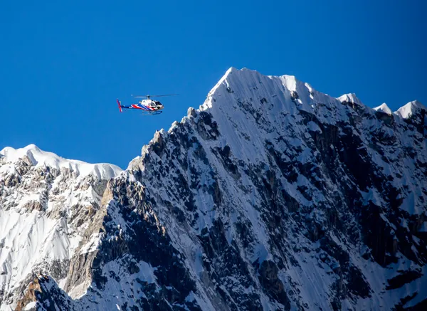 A rescue helicopter flying past the icy ridges of the Nuptse-Lhotse wall