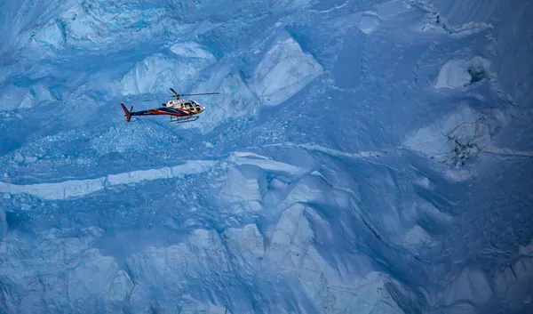 A high-altitude helicopter flight revealing the scale of blue Himalayan ice walls