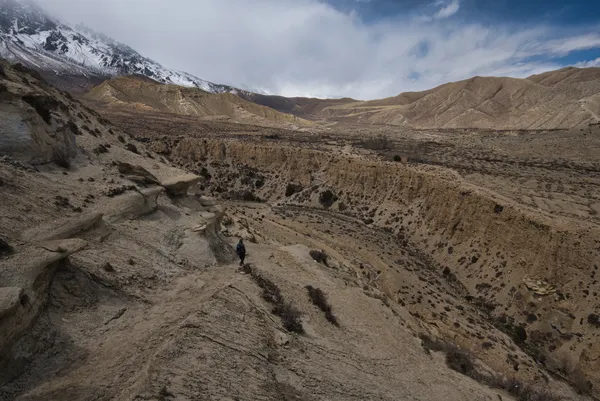 A trekker navigating arid canyons on the descent toward Dhi Village