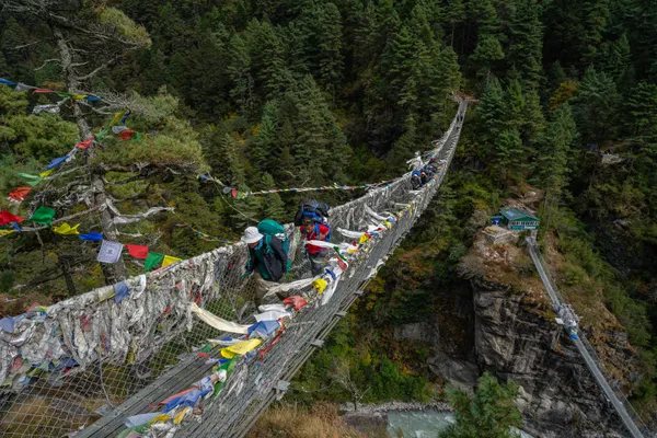 Trekkers on the famous suspension bridge draped in colorful prayer flags