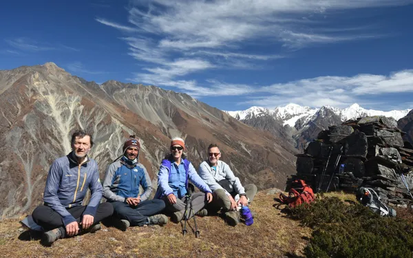 Trekkers resting on a hillside with mountain panorama