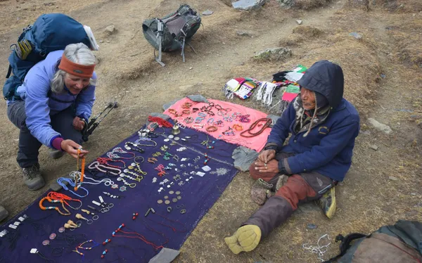 A merchant displaying traditional jewelry and souvenirs for a passing trekker at Larke Bazar