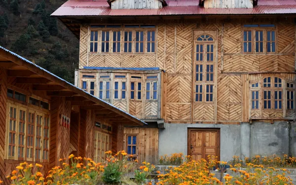 The ornate wooden facade of Lho Gumba monastery framed by orange marigolds