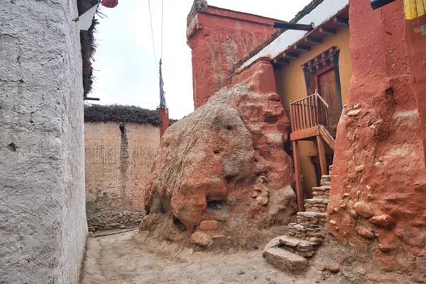 The red-walled cave monastery of Luri Gomba clinging to the cliffside above the valley