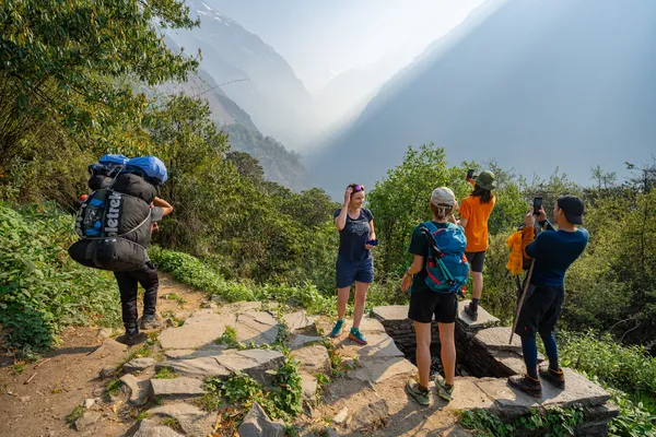 Trekkers stopping on a stone path above a misty mountain gorge