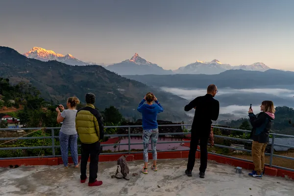 Trekkers capturing golden alpenglow on Himalayan summits at dawn