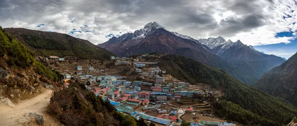 A traveler engaging with a prayer wheel at a mani stone shrine