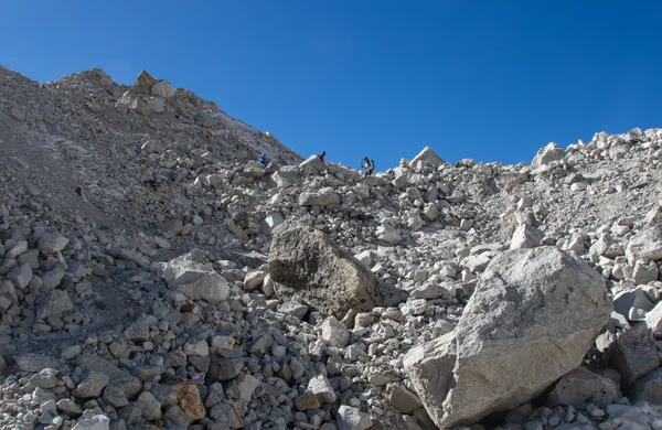 Trekkers picking their way through steep, lunar-like terrain west of the pass
