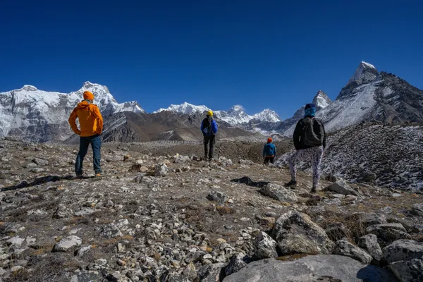 Trekkers gaze across the debris-covered Ngozumpa Glacier toward Everest and Lhotse