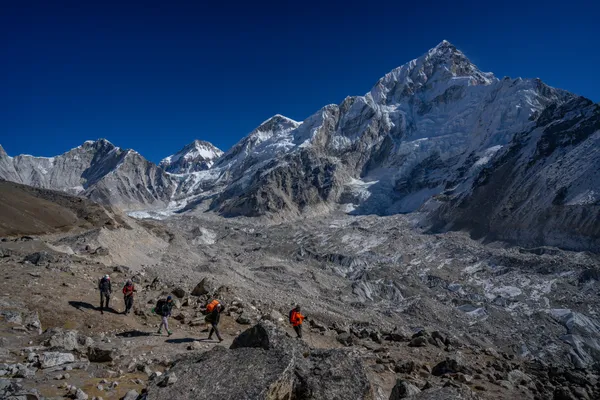 Trekkers navigating the rocky Khumbu Glacier moraine toward Pumori and Nuptse