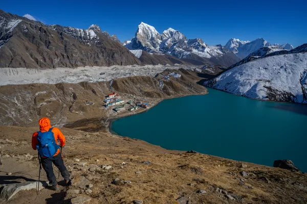 A hiker gazing at turquoise Gokyo Lake and the Ngozumpa Glacier
