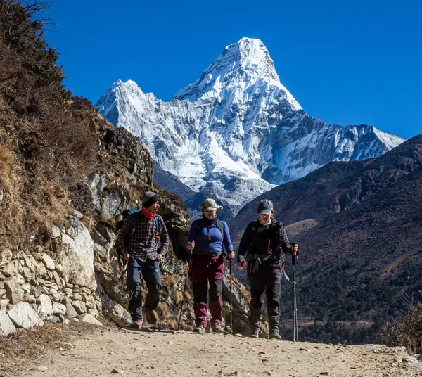 Trekkers descending the mountain path with Ama Dablam in the background