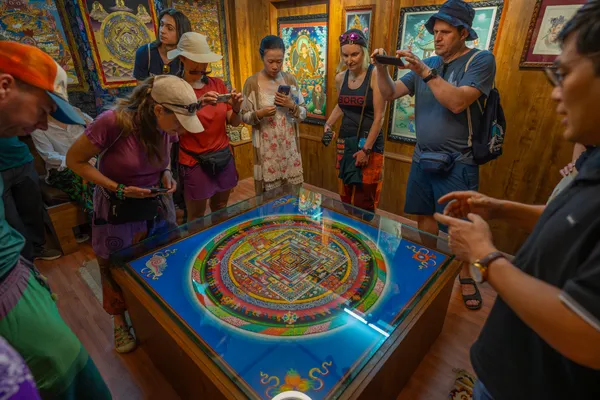 Visitors admiring the intricate geometry of a sacred Buddhist sand mandala