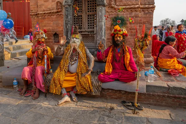 Holy men in traditional robes and face paint at a stone shrine