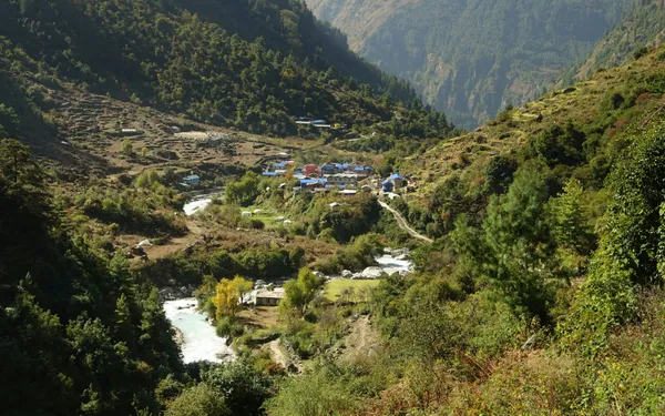 A village of painted rooftops between steep hillsides and a winding river