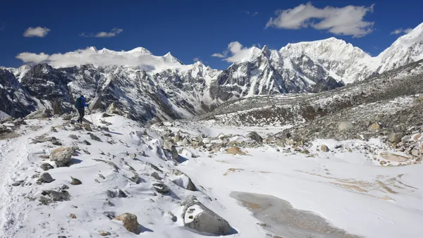 Fresh snow blanketing the ground beneath a clear blue sky and soaring peaks