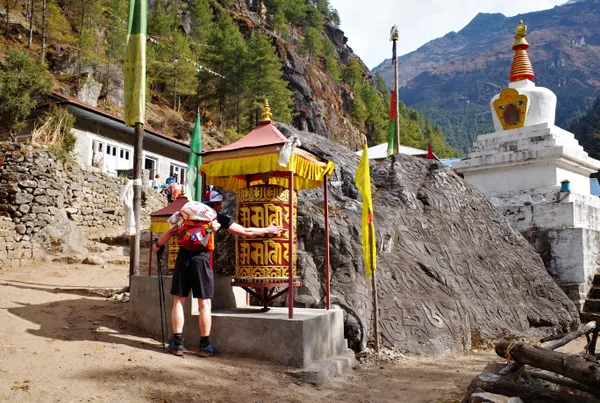 A trekker engaging with Buddhist traditions at a mani stone shrine