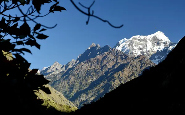 A white peak gleaming under a clear sky above a river gorge