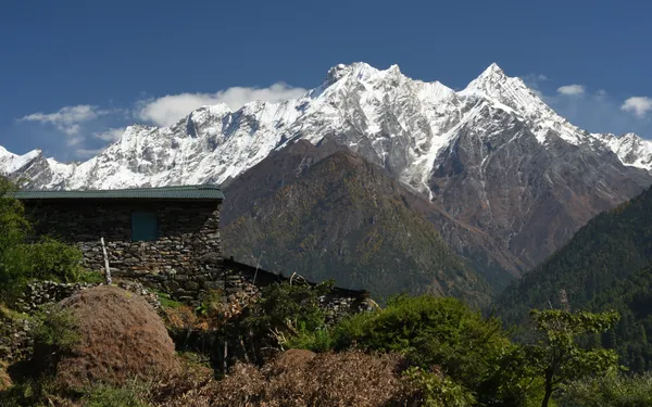 A traditional stone dwelling against snow-covered peaks