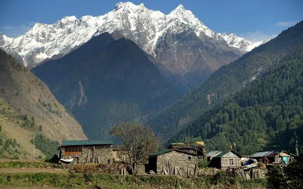Compact stone houses at the base of snow-draped mountains