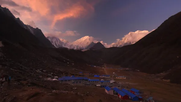 The evening sky turning pink and orange over the blue-roofed houses of Bimthang