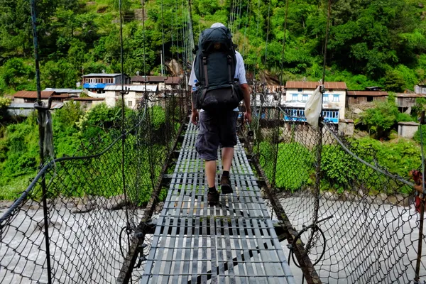 A trekker crossing a suspension bridge
