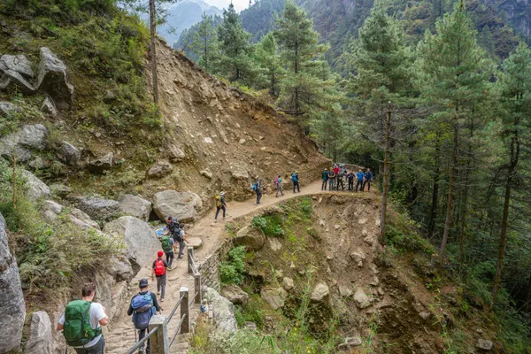 Hikers on a rugged trail dropping toward the riverbank